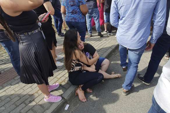 Women sit in an embrace outside the Cantinho do Bom Pastor daycare centre after the fatal attack.
