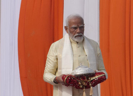 Indian Prime Minister Narendra Modi carries a sacred item during the opening of the temple.