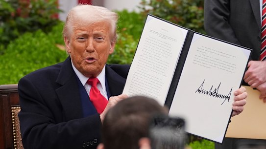 President Donald Trump holds his signed executive order on international trade tariffs.