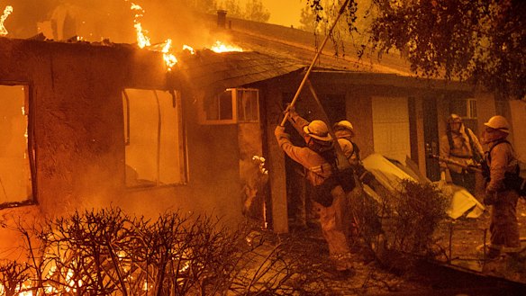 Firefighters work to keep flames from spreading through the Shadowbrook apartment complex as a wildfire burns through Paradise, California.