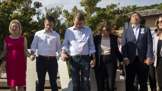 2020 Democratic presidential candidates hold hands as they stand together during a moment of silence to honour victims of recent mass shootings.