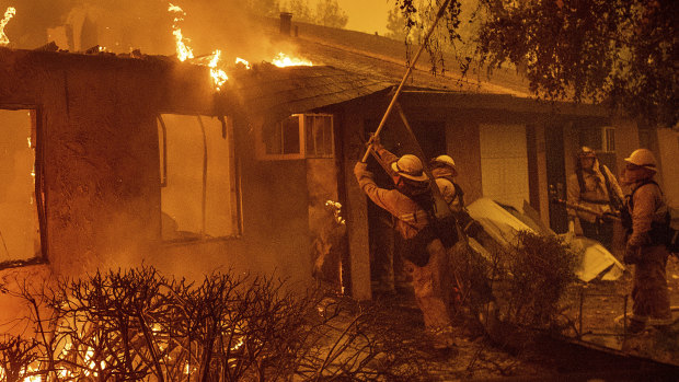 Firefighters work to keep flames from spreading through the Shadowbrook apartment complex as a wildfire burns through Paradise, California.