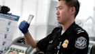 A traveller arriving at Newark International Airport is fingerprinted (L) while his paperwork is checked by a US border patrol official.