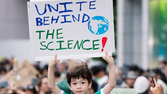 A boy holds up a placard while joining a rally, calling for action to guard against climate change in Tokyo on Friday.