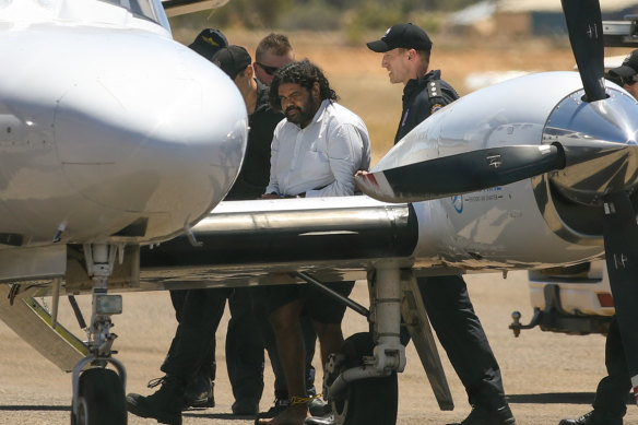 Terence Darrell Kelly, centre, boards a plane after being taken into custody by members of the Special Operations Group at Carnarvon airport on Friday.