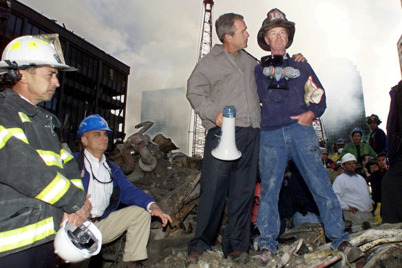Then-US president George W. Bush stands with firefighter Bob Beckwith  on a burnt fire truck in front of the World Trade Centre during a tour of the devastation in September 2001.