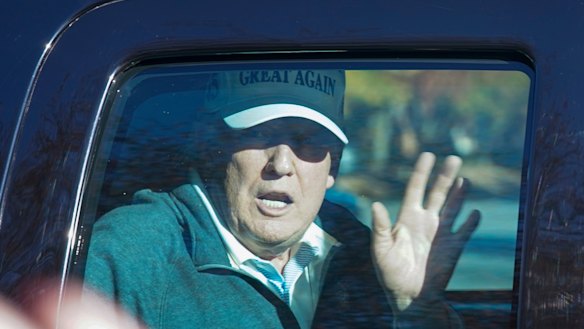 President Donald Trump waves to supporters as he departs after playing golf on Sunday.