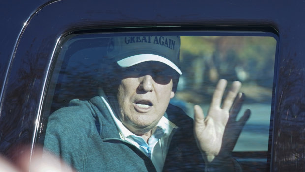 President Donald Trump waves to supporters as he departs after playing golf on Sunday.