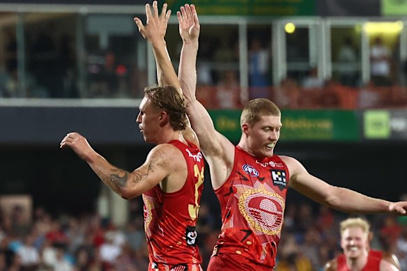 Sam Clohesy of the Suns kicks a goal and celebrates with Matt Rowell.
