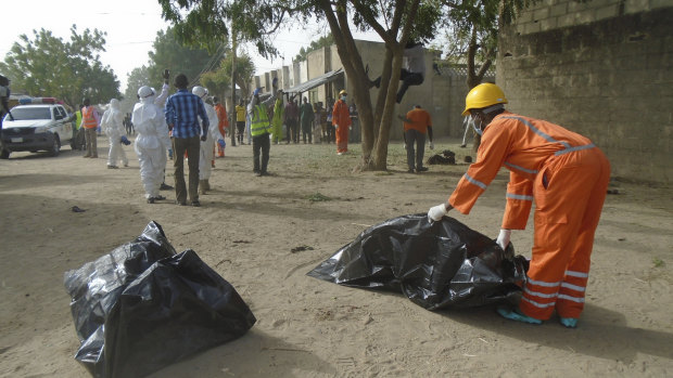 Emergency personnel collect bodies following an attack by suicide bombers at the outskirts of Maiduguri, Nigeria.