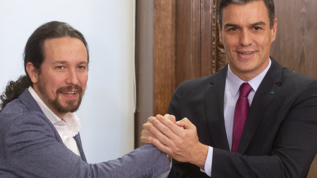 Spain's caretaker Prime Minister Pedro Sanchez, right, and Podemos party leader Pablo Iglesias clasp hands after signing an agreement between the two parties in the Spanish Parliament in Madrid.
