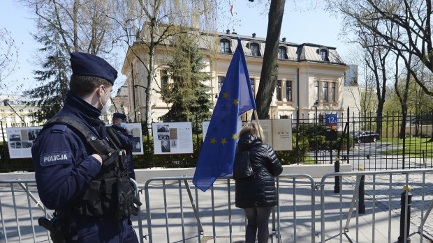 A woman holds a European Union flag outside the Constitutional Tribunal, background in Warsaw.