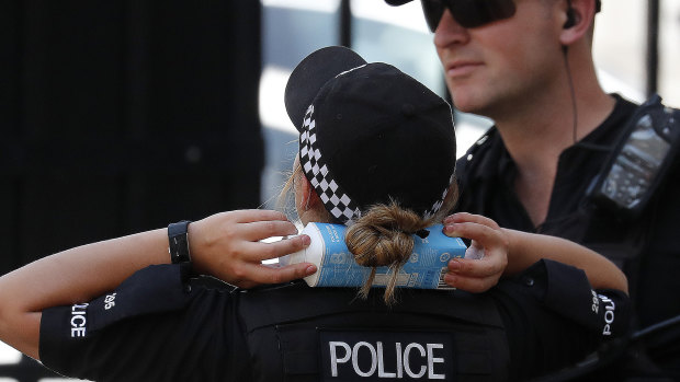 A police officer cools down with a drink carton held on her neck as temperatures pass 38 degrees in London on Thursday.