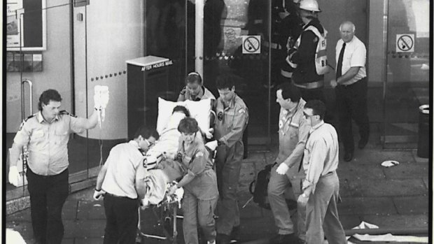 Ambulance workers take one of bombing victims out of the NCA building in Adelaide.