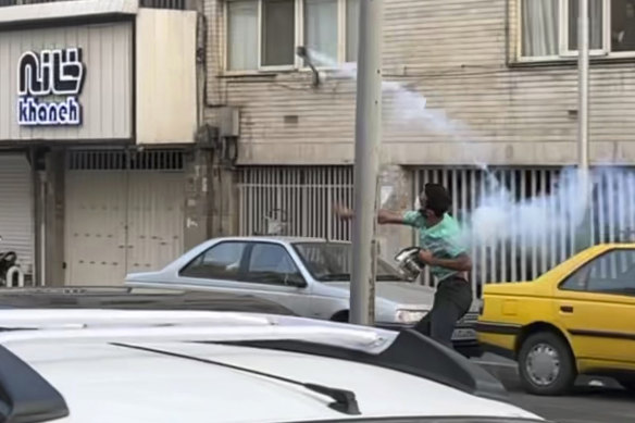 A demonstrator in Tehran throws tear gas back at Iran’s anti-riot police during a protest over the death of a young woman.