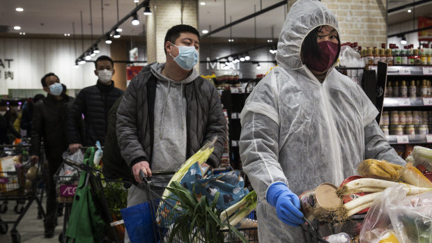 Chinese residents wear protective gear as they line up in a supermarket in Wuhan. 