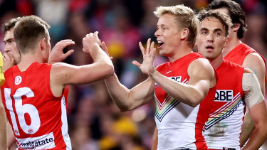 Isaac Heeney (centre) celebrates with teammates after kicking a goal for the Swans.