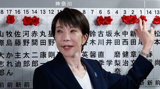 Sanae Takaichi places a red rose on the name of one of her winning candidates at the LDP party’s headquarters.