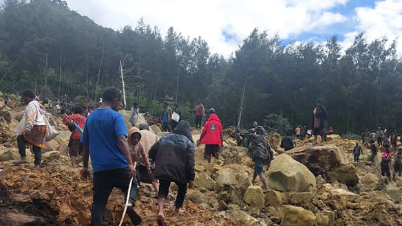 In this photo provides the International Organization for Migration, people cross over the landslide area to get to the other side in Yambali village, Papua New Guinea, Friday, May 24, 2024. More than 100 people are believed to have been killed in the landslide that buried a village and an emergency response is underway, officials in the South Pacific island nation said. The landslide struck Enga province, about 600 kilometers (370 miles) northwest of the capital, Port Moresby, at roughly 3 a.m., Australian Broadcasting Corp. reported. (Benjamin Sipa/International Organization for Migration via AP)