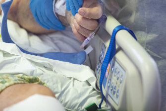 A nurse holds the hand of a COVID patient in intensive care at St. Luke’s Boise Medical Centre in Boise, Idaho, in August 2021. 