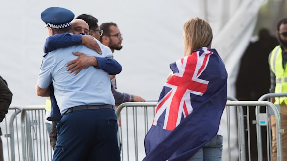A policeman hugs a mourner at the gravesides.