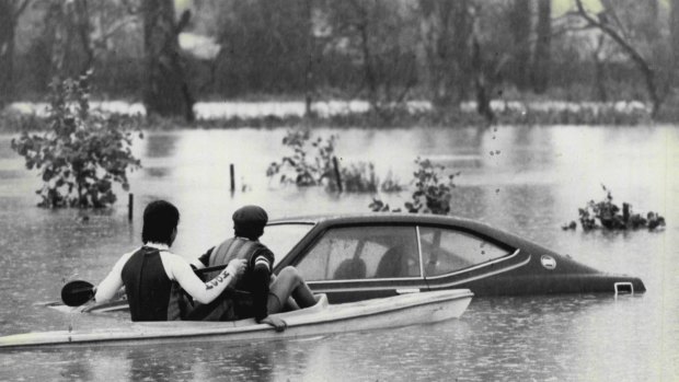 Two people in a canoe inspect a flooded car at Lansvale, August 6, 1986.