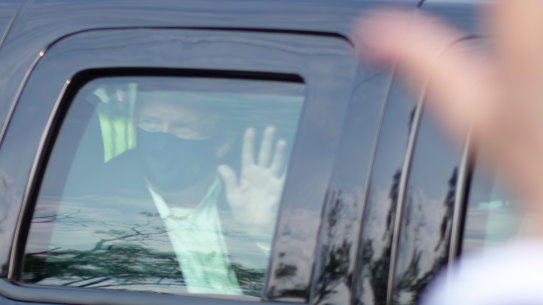 President Donald Trump, who has tested positive for coronavirus, drives past supporters gathered outside the hospital where he is being treated.
