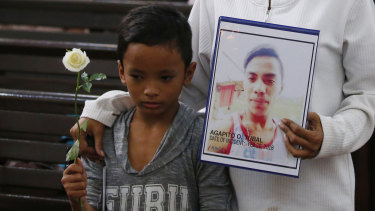 A boy stands next to his mother, who holds a portrait of his brother, an alleged victim of President Rodrigo Duterte's 'war on drugs', during a religious service in Manila last month.