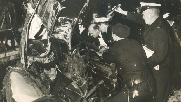 Dr John Birrell, in a dinner jacket, examines a wreck. The car smashed into a power pole at more than 100 miles an hour killing the occupants.