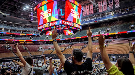 Vaccine recipients at Scotiabank Arena, Toronto, cheer for giveaways as the number of doses administered reaches 25,000. The venue went on to set a North American record of 26,771 jabs in a day. 
