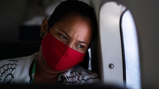 Telma Maria looks out of the window as a doctor monitors her 89-year-old father who is suffering from COVID-19 and is being airlifted to a hospital in Manaus, Brazil.