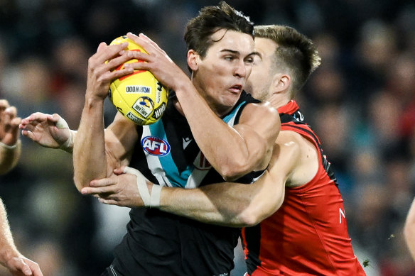 Connor Rozee of the Power tackled by  Zach Merrett of the Bombers.