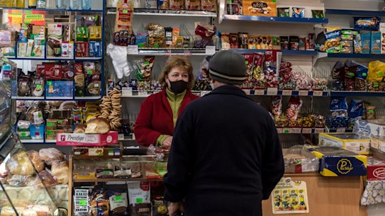 Olga Kotesova serves a customer, some of whom live in a buffer zone between separatists and Ukrainian government forces, at her small shop in Hranitne, Ukraine.