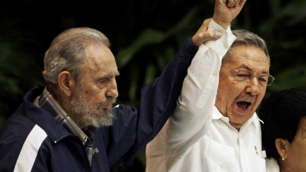 Fidel Castro, left, raises the hand of his brother President Raul Castro as they sing the international socialism anthem in 2011.