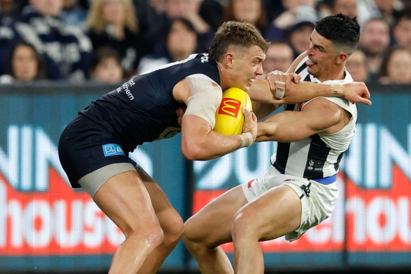 Patrick Cripps of the Blues attempts to fend off a tackle from Scott Pendlebury of the Magpies.