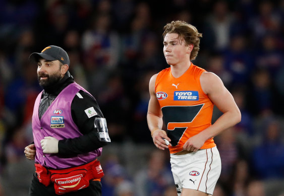 Tanner Bruhn leaves the field with a member of the GWS medical staff.