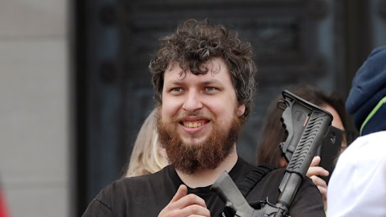 Kevin King cradles an assault rifle as he stands on the top of the Capitol steps at a protest opposing Washington state's stay-home order to slow the coronavirus outbreak on Sunday, in Olympia.