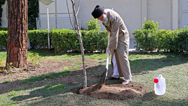 Supreme Leader Ayatollah Ali Khamenei, wearing gloves, participates in a tree planting ceremony in Tehran, Iran.