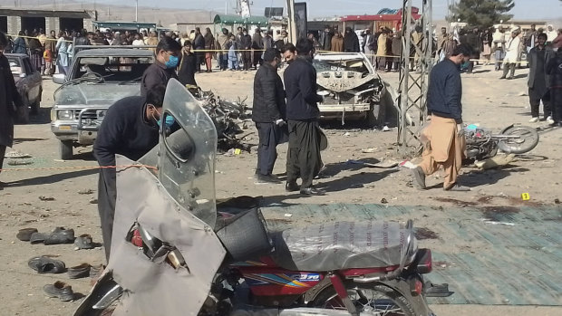 Security officials examine the scene of a bomb blast in Pakistan one day before elections are held.