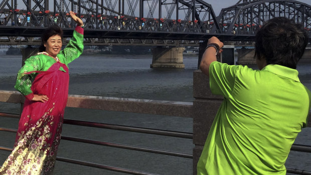 Chinese tourists in North Korean costumes pose for souvenir photos near the Friendship Bridge connecting China and North Korea.
