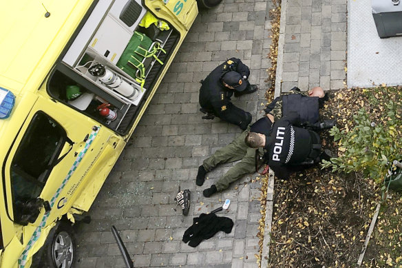 Police detain a main next to a damaged ambulance in Oslo.