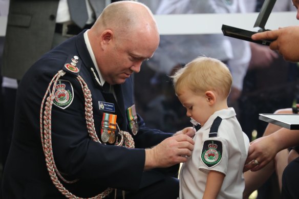 RFS Commissioner Shane Fitzsimmons pins the service medal of Geoffrey Keaton onto his son, Harvey.