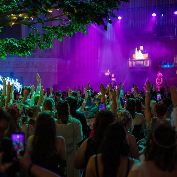 Ball attendees do the three-finger salute from the Hunger Games series.
