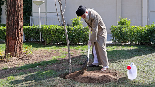 Supreme Leader Ayatollah Ali Khamenei, wearing gloves, participates in a tree planting ceremony in Tehran, Iran.