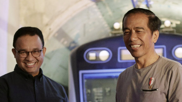 Indonesian President Joko  Widodo, right, shakes hands with Jakarta Governor Anies Baswedan with the background of a Jakarta Mass Rapid Transit train during the inauguration ceremony of the subway line system in Jakarta on Sunday.