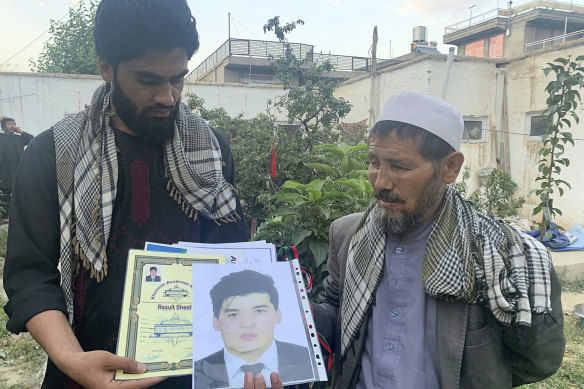 Mohammed Jan Sultani’s father, Ali, right, looks at his son’s Taekwondo championship certificates along with his picture.