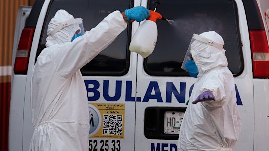 Ambulance workers disinfect each other after delivering a patient to the COVID-19 triage unit at Mexico General Hospital. 