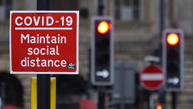 A social distancing sign is affixed next to traffic light signals ahead of the lockdown closure of bars, gyms and clubs in Liverpool.