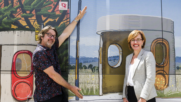 Canberra artist Trevor Dickinson and Transport Minister Meegan Fitzharris in front of a bus wrapped in his iconic bus stop artworks.