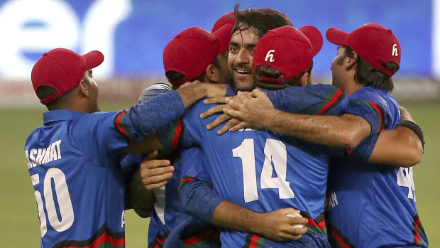 Breakthrough: Afghanistan players congratulate Rashid Khan, centre without cap, after he dismissed India's last wicket of Ravindra Jadeja.